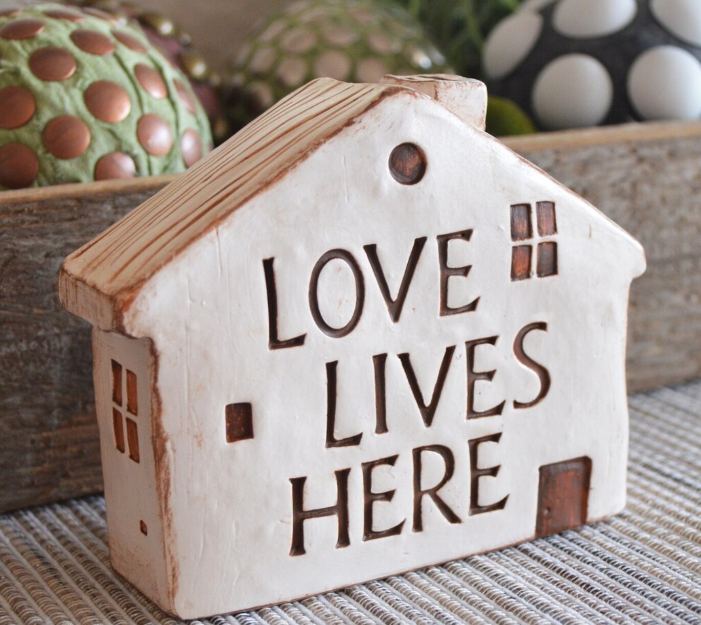 Clay house with words love lives here house text on house tabletop
