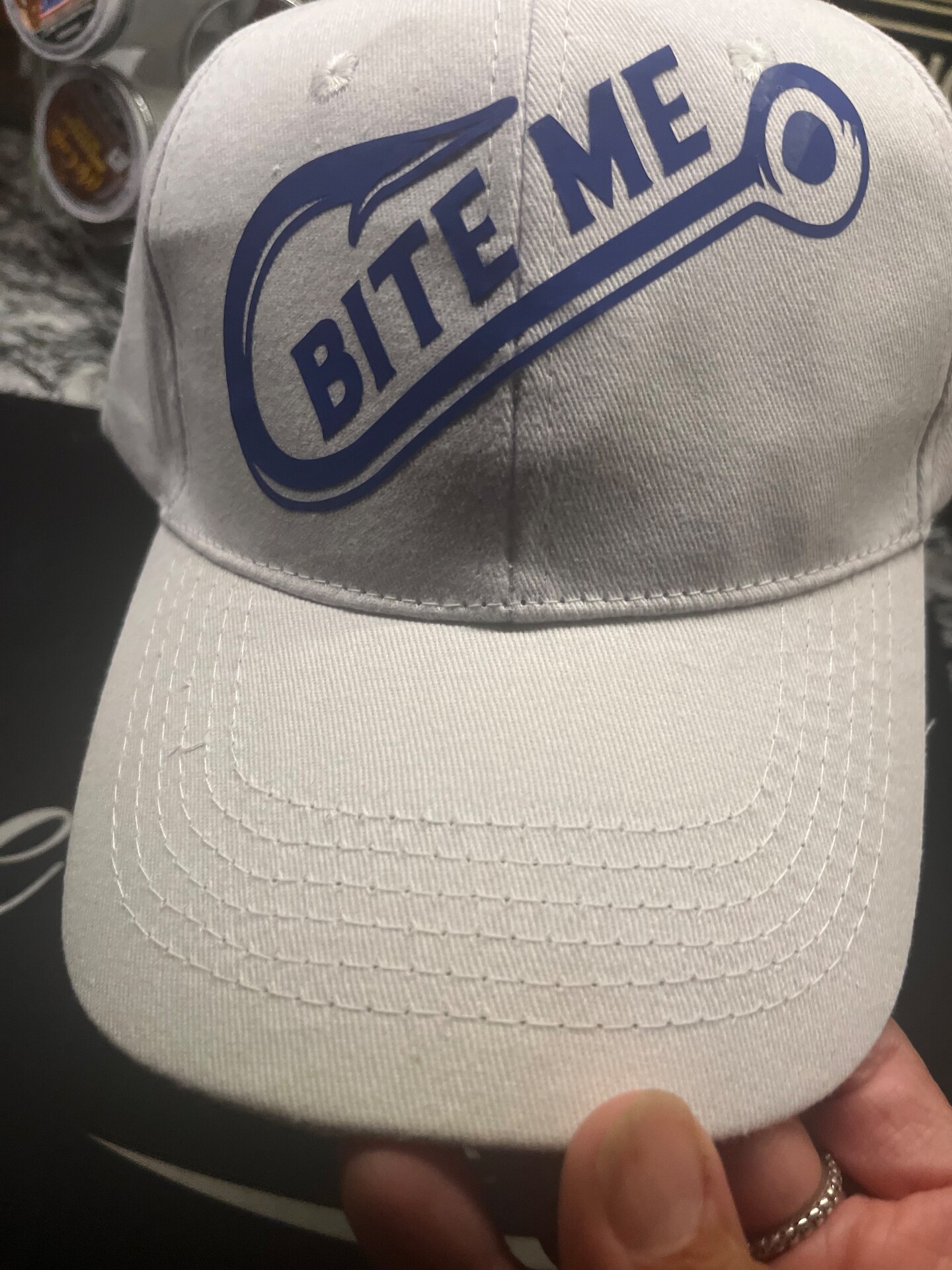 Bite me fishing hook baseball cap. Adjustable size, canvas cotton cap. Fish  hook logo and words “bite me” over hook.