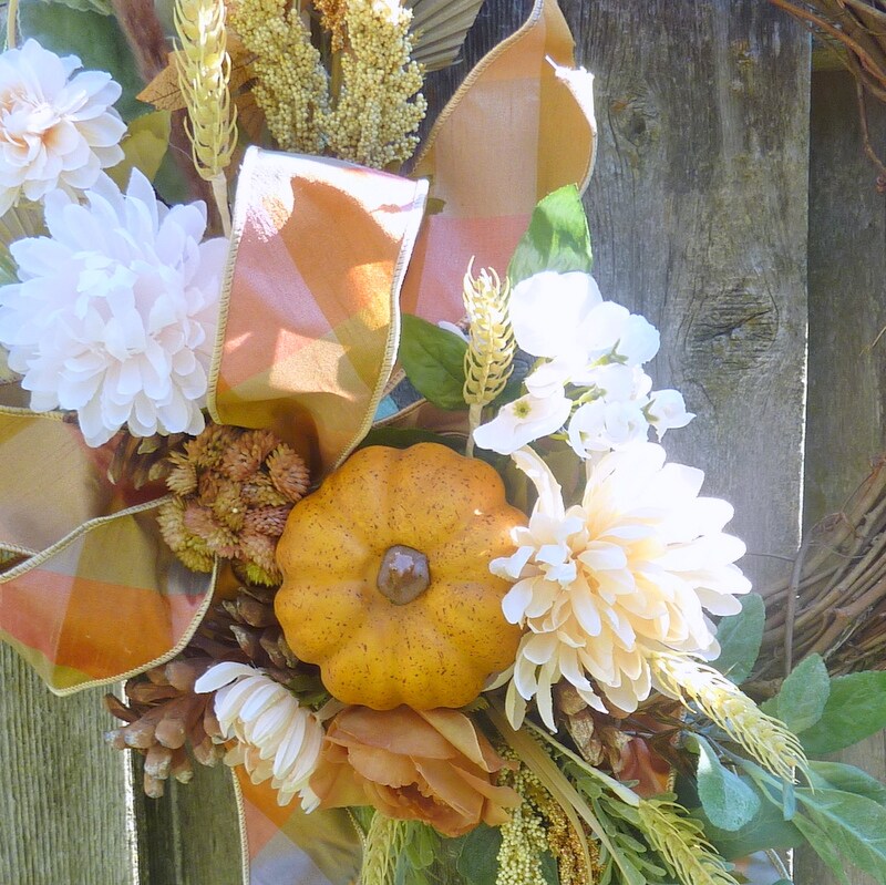 Fall Grapevine wreath orange ,white florals and blue berries with beautiful greenery. Adorned with beautiful popular ribbon and pumpkins .