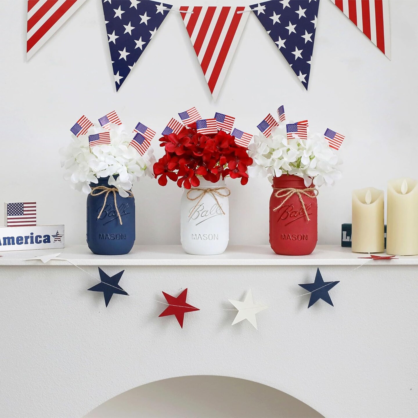 Patriotic table decor with mason jars, mini flags, and red, white, blue accents.