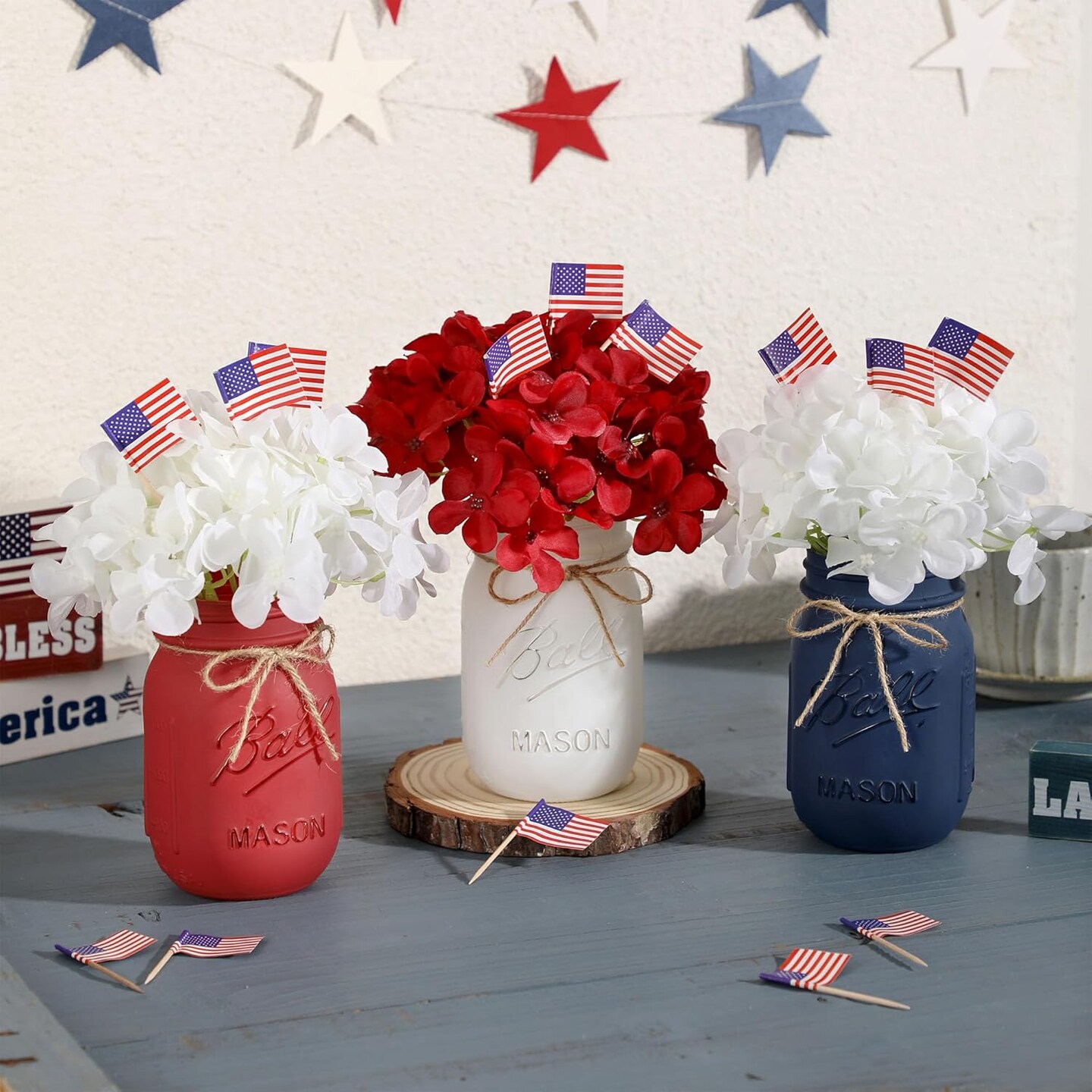 Patriotic table decor with mason jars, mini flags, and red, white, blue accents.