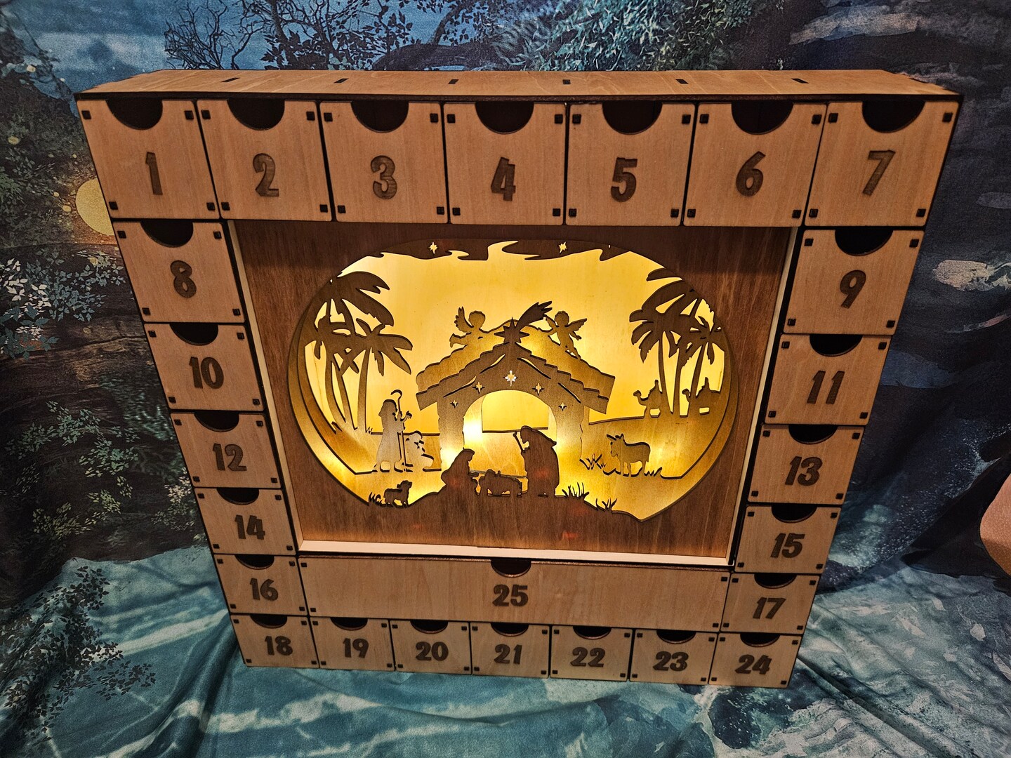 Lighted advent calendar featuring a nativity scene Christmas decoration featuring large drawers to hide treats for each day.