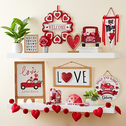 Valentine's Day home décor signs and banners displayed on white shelves.