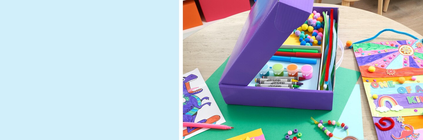 kids craft supplies in activity box on wood table