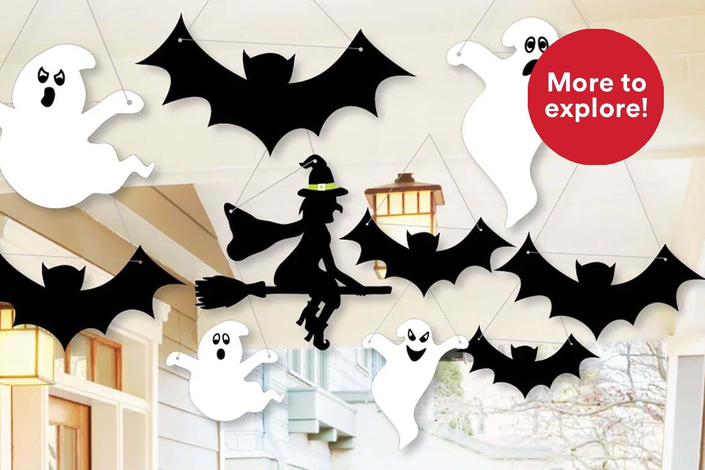 ghost and bat cut outs hanging from porch ceiling with More to Explore logo in red bubble