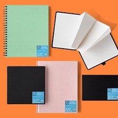 Hard and wire bound sketchbooks laid out on orange background
