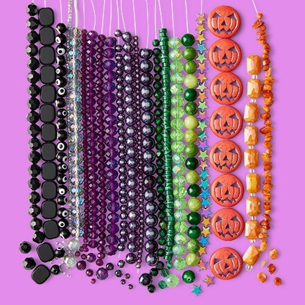 assorted black, purple, green and orange strung beads on purple background