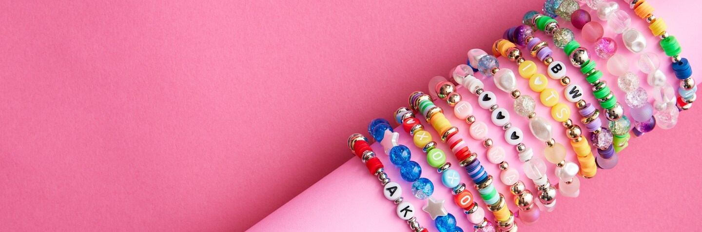 stack of assorted bead friendship bracelets on pink form with pink background