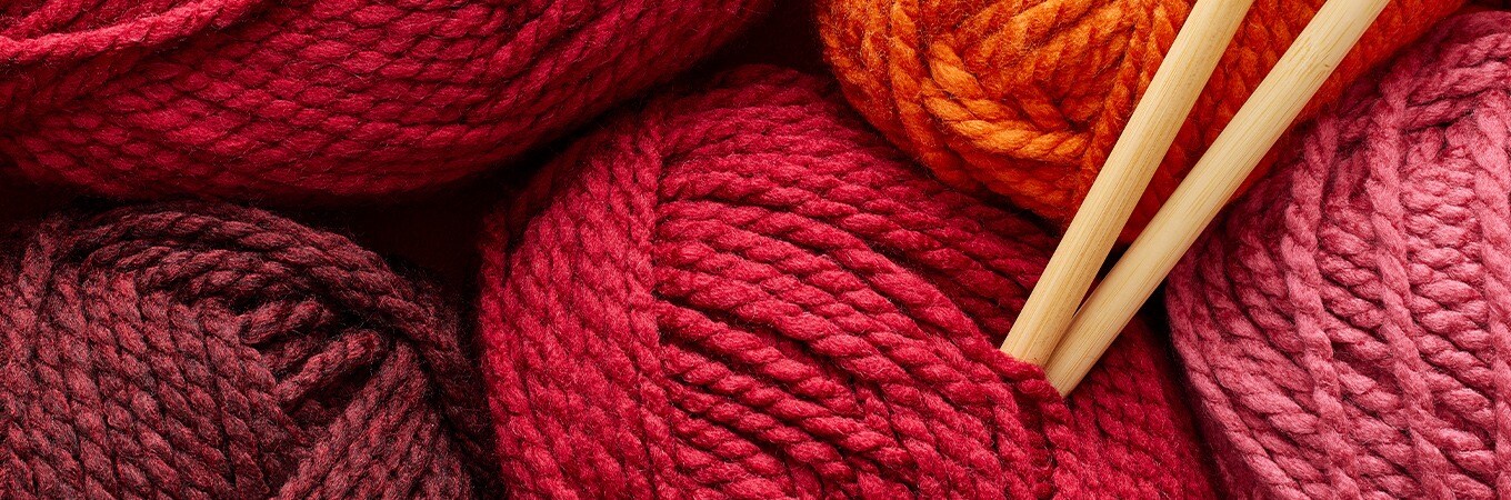 Image of multiple shades of red and orange yarn balls.