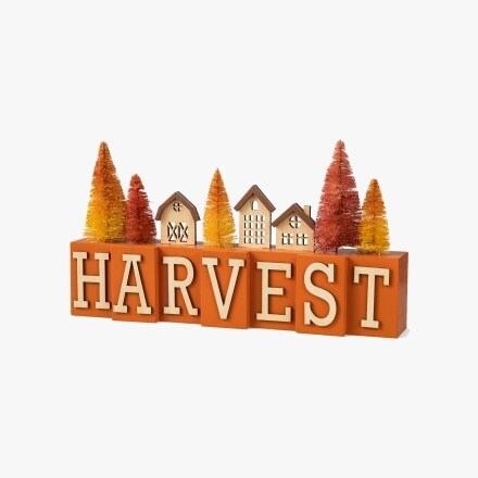 Tabletop decor item with the word "Harvest", with some small houses and trees in orange colors