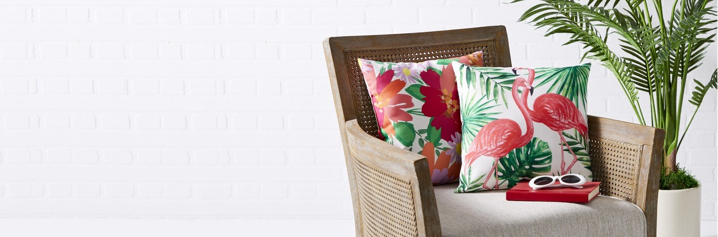 Armchair with Summer Pillows with pink Flamingos and Flowers and a floor plant