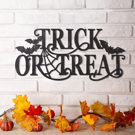 Wall sign that says Trick or Treat in black letters with decorative bats