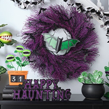 Purple decorative Wreath with a green bat and some other tabletop decorations