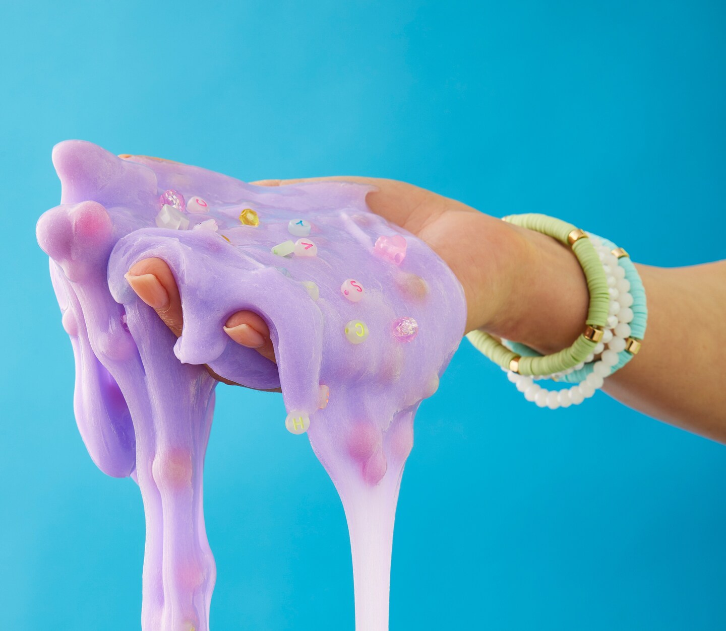 Slime falling from someone's hand in front of a blue background.