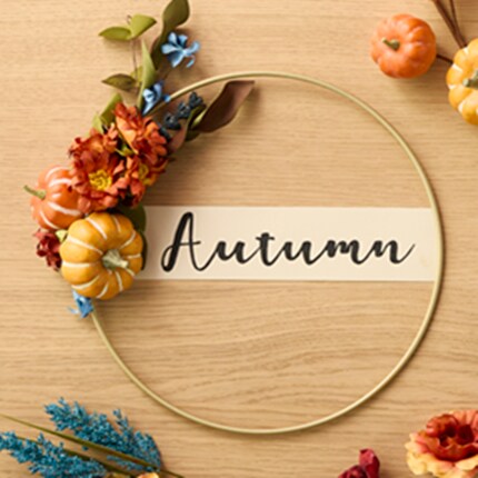 A wreath with flowers and pumpkins on a wood surface