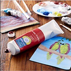 Red oil paint tube on table with parrot painting