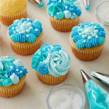 cupcakes decorated with blue shades of icing and white sprinkles