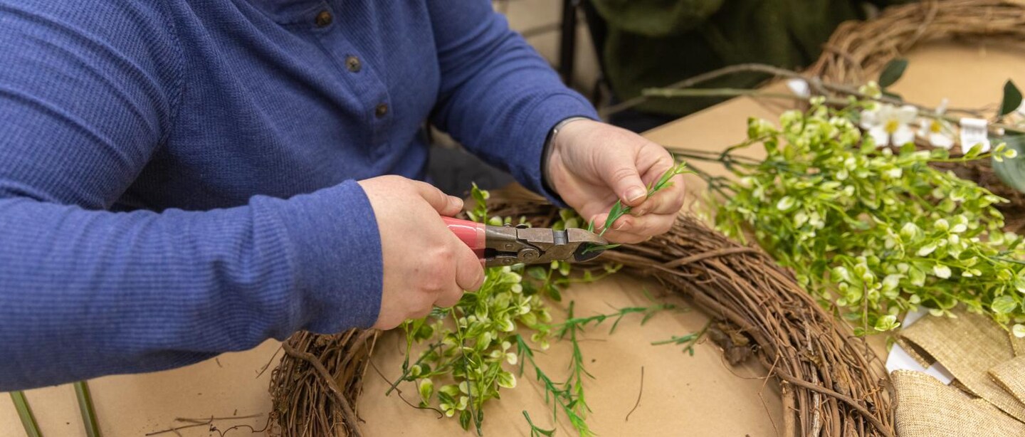 A pair of hands clips a floral stem