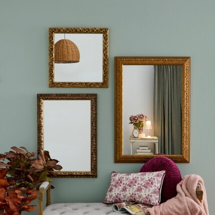 Three framed mirrors hanging on a light green wall