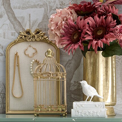 Gold vase with burgundy flowers and romantic jewelry display with a white bird