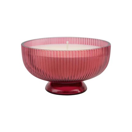 Pink ribbed glass candle bowl, filled with white wax and a centered wick, isolated on white; elegant, calming decor.