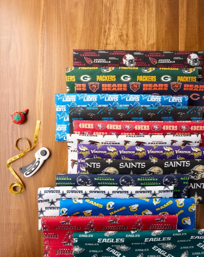 sport team fabric rolls against a wooden background, with sewing notions on the side