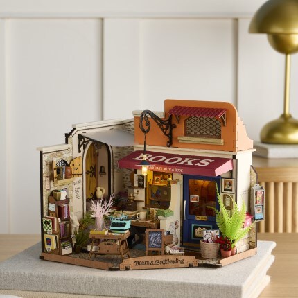 Bookstore miniature kit featuring outside of bookstore with red awing, plants, and book displays. 