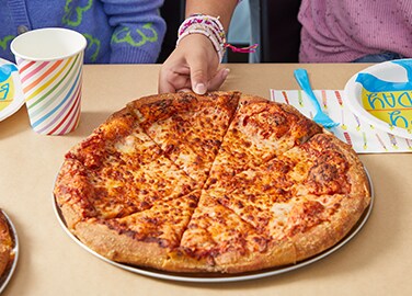 A hand reaches for a slice of pizza