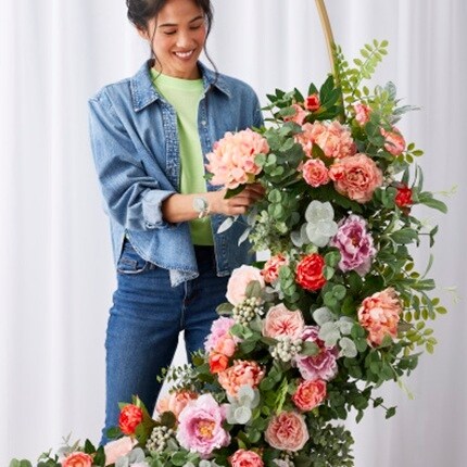 woman attaching pink flowers to floral arrangement