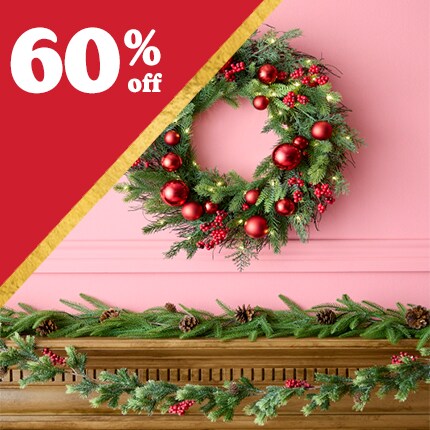 green wreath with red ornaments on pink wall above wood mantel with evergreen garland with 60% off in white text over red triangle