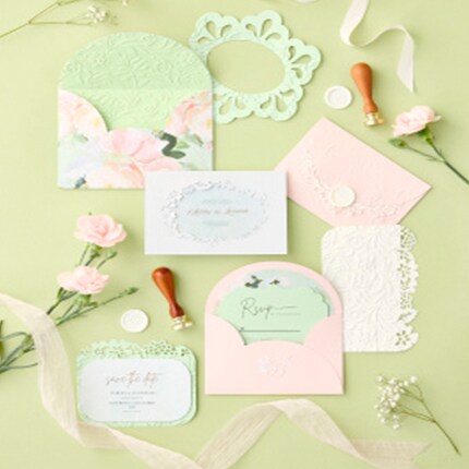 pink and green floral invitations with envelopes on green table with flowers and wax seals