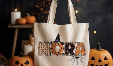 MakerPlace by Michaels Halloween-themed canvas tote bag reading “NOPE,” decorated with a witch hat and spiderweb, surrounded by glowing pumpkins and candles.