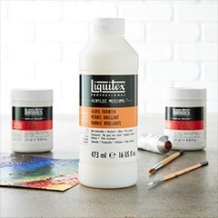 White liquitex paint medium bottle on table with paint brushes