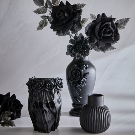 Three matte black vases with intricate floral designs and textures, including two large black roses and detailed leaves in one vase. 