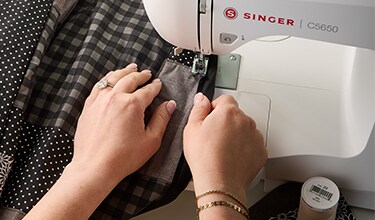 hands sewing quilted black and gray jacket