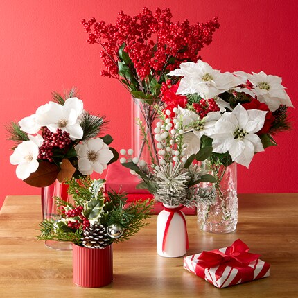 A group of vases with poinsettias and berries.