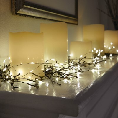 mini lit craft lights surrounding cream candles sitting on top of a white mantle 