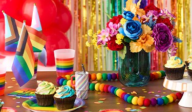 Rainbow-striped unicorn decoration, rainbow flags, and a vase with vibrant flowers in blue, purple, yellow, and orange. 