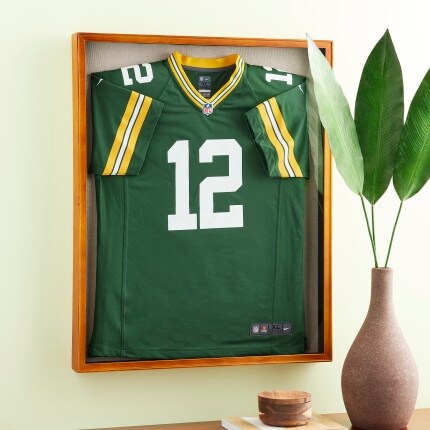 green jersey in light wood shadow box on pale yellow wall