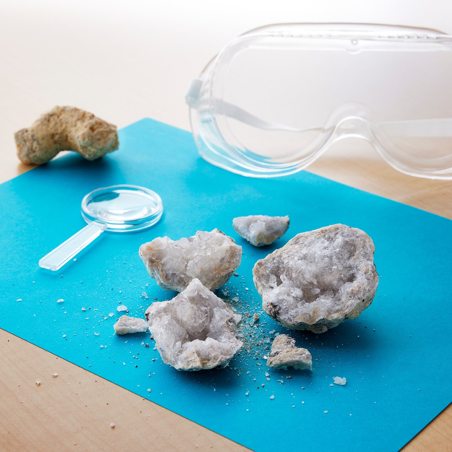 Geode broken next to a magnify glass and goggles