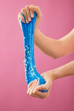 hands pulling blue slime with pink background