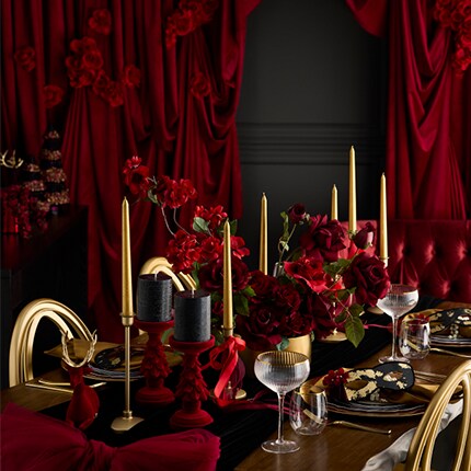 black and gold table settings with decor accents and velvet red curtains in the background