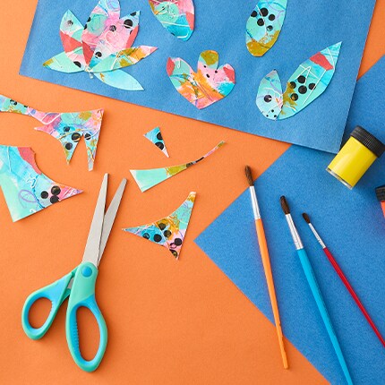 Paper art project with construction paper, scissors, and paint brushes. 