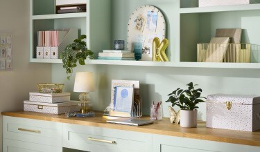 Artful Organization Decor Collection: desk with decor boxes with a white and gold pattern, a lamp and other gold tabletop decorations