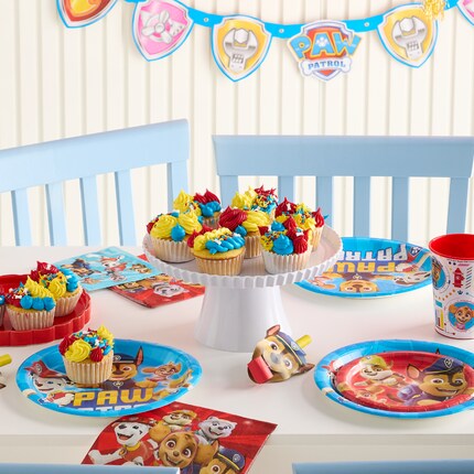 Paw Patrol-themed birthday setup with a Chase balloon centerpiece, Paw Patrol banner, colorful balloons, themed tableware, and decorated cupcakes. Festive and cheerful.