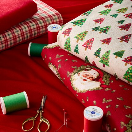Christmas Fabric with Santa and Christmas Trees on a table with thread