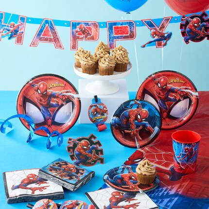A vibrant Spider-Man themed party setup with a Spider-Man balloon, a decorated cake, themed paper cups and plates, and colorful balloons in the background.