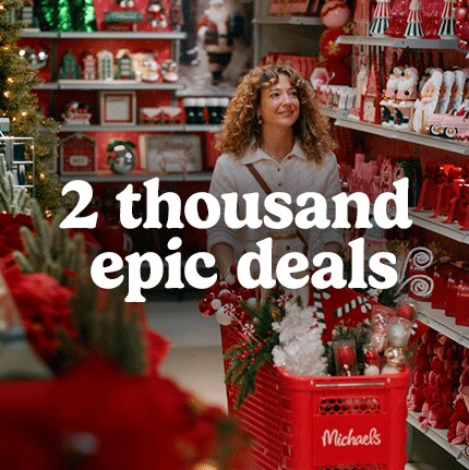 A woman smiles while shopping in a festive store aisle filled with Christmas decorations. She pushes a red cart with holiday items. Text reads, "2 thousand epic deals."
