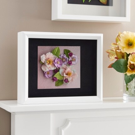 white shadowbox frames with black backing and flowers on white mantel