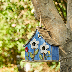 Blue birdhouse in a tree with a flower design